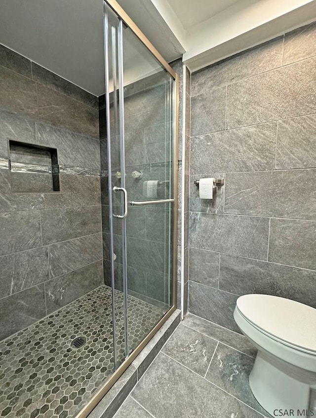 bathroom with a shower with door and toilet