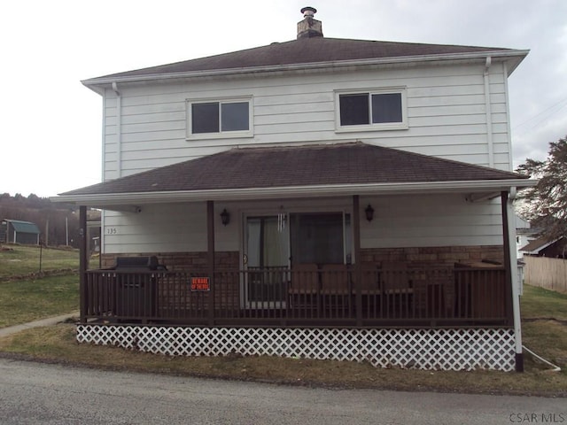 exterior space with a chimney, a shingled roof, and a porch