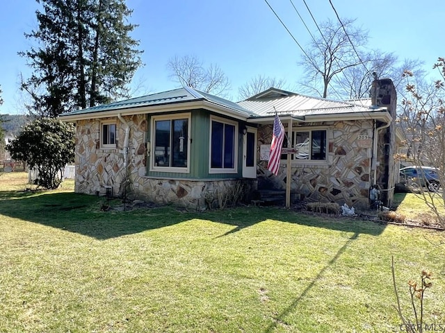 view of front of house with a chimney, a front yard, metal roof, and stone siding