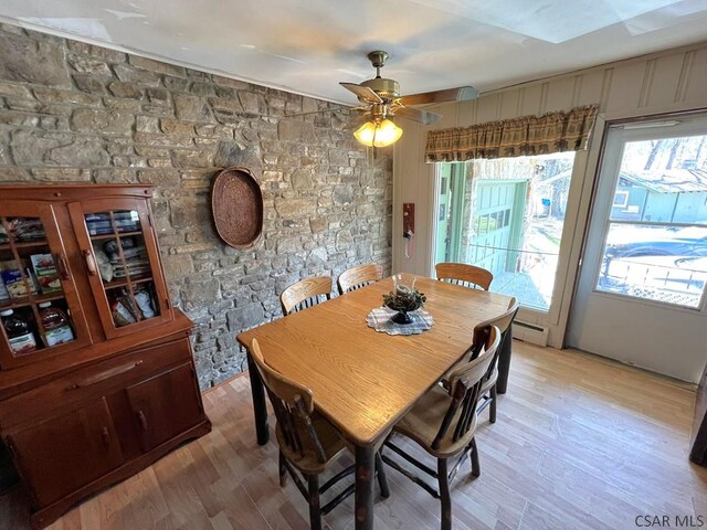 dining room with a healthy amount of sunlight, light wood finished floors, and a baseboard heating unit