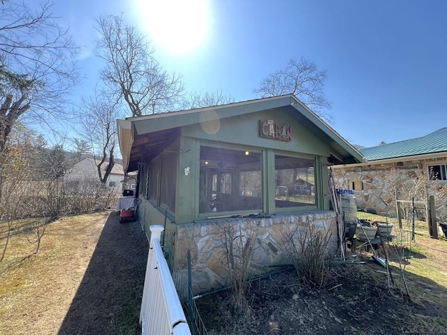 view of side of property featuring metal roof and stone siding