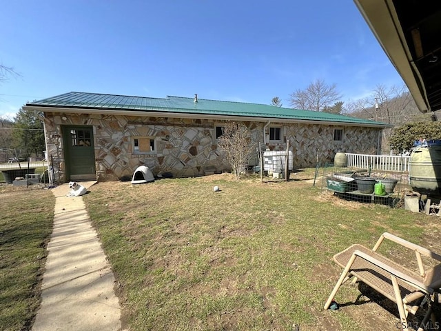 back of house featuring metal roof, a yard, and stone siding