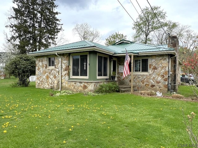 view of front of home featuring metal roof, a front yard, stone siding, and fence