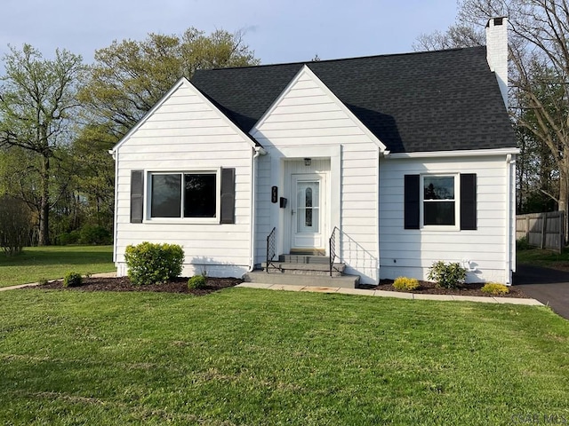 view of front of home with fence, a shingled roof, a chimney, and a front yard
