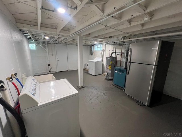 below grade area featuring freestanding refrigerator, water heater, washer and clothes dryer, and a wealth of natural light