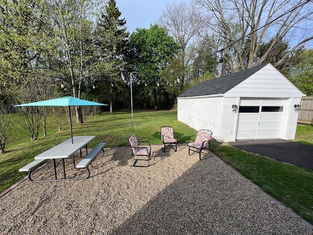view of yard featuring an outdoor structure, a garage, and aphalt driveway