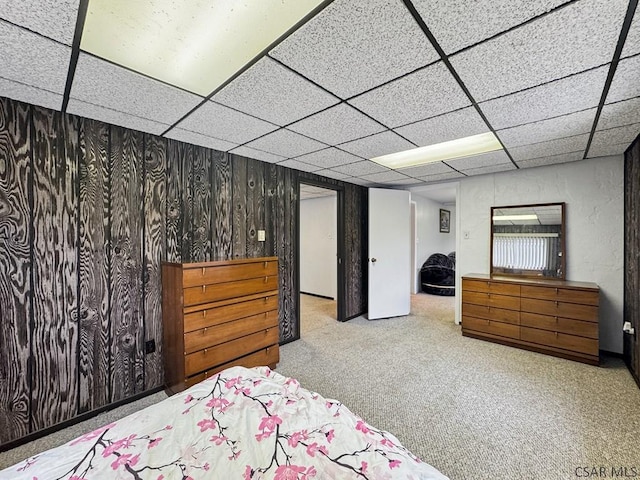 carpeted bedroom featuring a paneled ceiling and wood walls