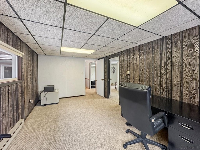 carpeted office space featuring a baseboard radiator and wooden walls