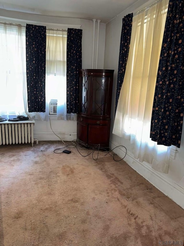 spare room with radiator heating unit, a wall mounted AC, and carpet floors