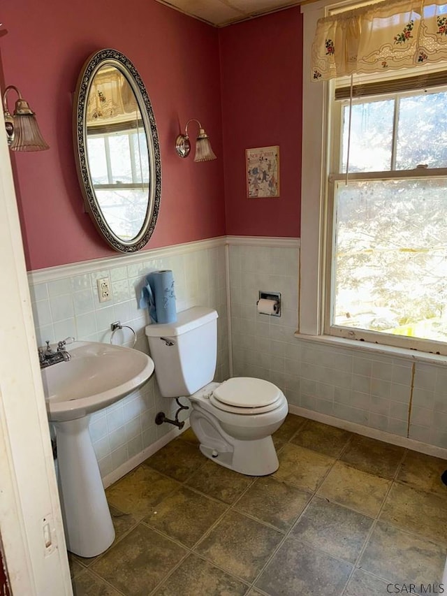 bathroom featuring toilet and tile walls