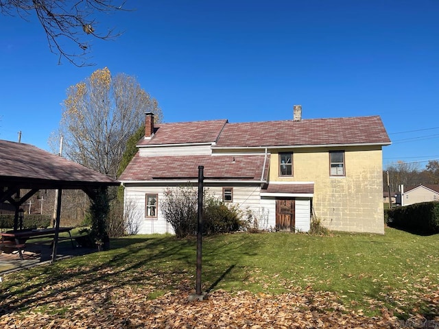 back of property with a yard and a gazebo