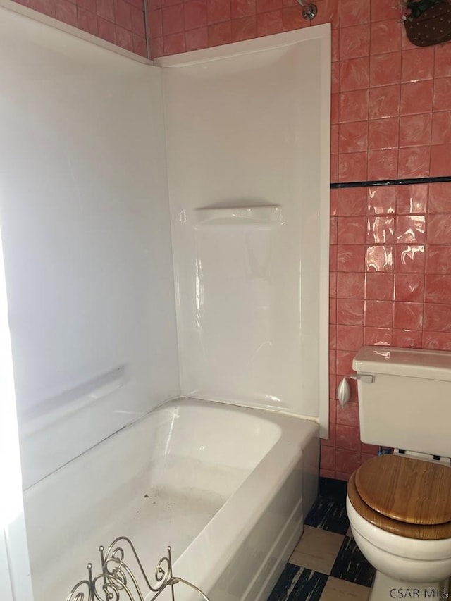 bathroom featuring toilet, shower / bathing tub combination, and tile walls