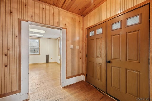 foyer with light hardwood / wood-style floors, wooden ceiling, and wood walls