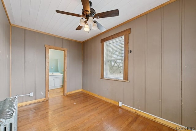 unfurnished room featuring crown molding, radiator heating unit, ceiling fan, and light wood-type flooring