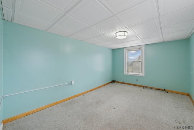 spare room featuring a paneled ceiling and light carpet