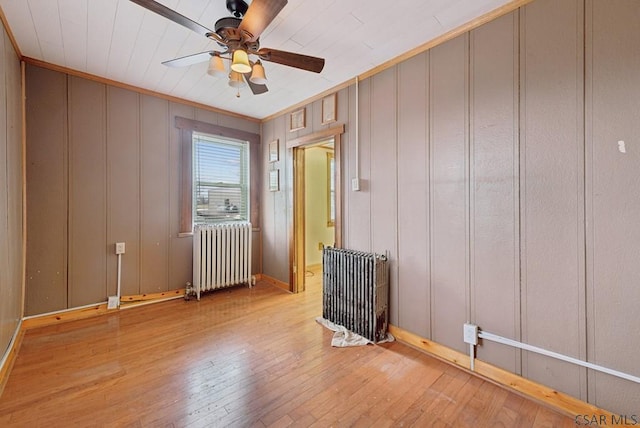 spare room featuring crown molding, ceiling fan, radiator heating unit, and light hardwood / wood-style floors