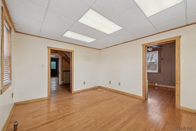 spare room with radiator heating unit, wood-type flooring, ornamental molding, and a paneled ceiling