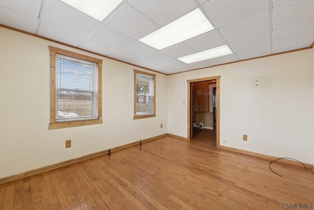 empty room with light hardwood / wood-style flooring, ornamental molding, and a paneled ceiling