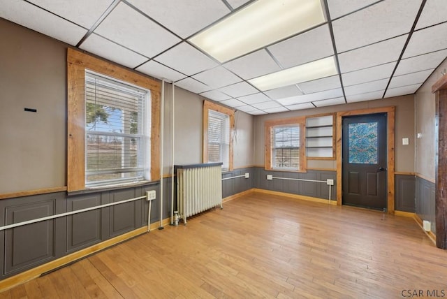 interior space with radiator heating unit, light hardwood / wood-style floors, and a paneled ceiling