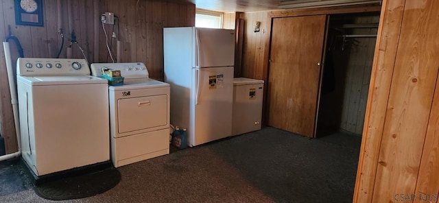 clothes washing area featuring dark colored carpet, washing machine and clothes dryer, and wood walls