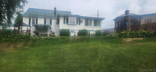 rear view of property featuring a yard and a gazebo