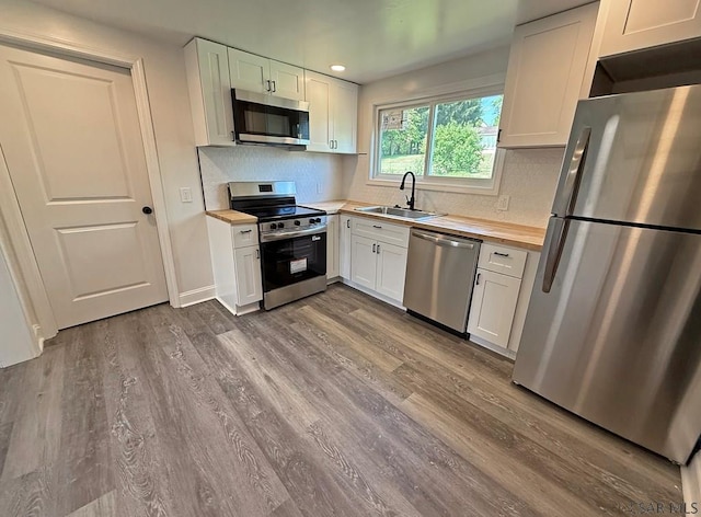247 Jefferson Ave, Windber, PA 15963 - kitchen featuring appliances with stainless steel finishes, wood counters, dark wood-style flooring, white cabinets, and backsplash