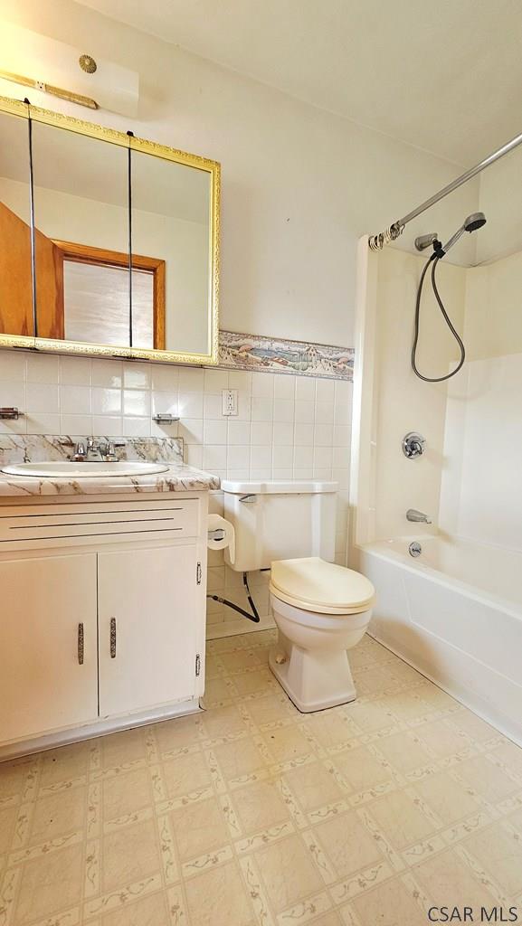 2139 Woodcrest Dr, Johnstown, PA 15905 - bathroom with toilet, vanity, shower / tub combination, tile patterned floors, and tile walls