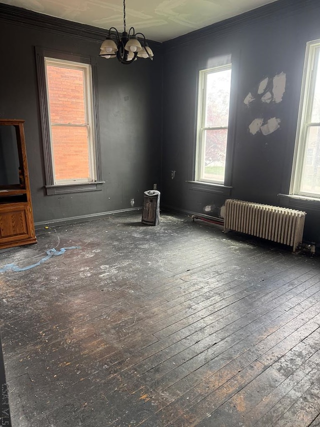 unfurnished dining area featuring crown molding, an inviting chandelier, a healthy amount of sunlight, and radiator heating unit
