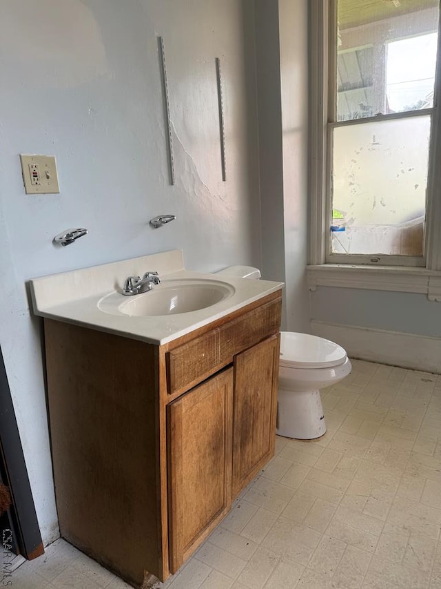half bathroom with vanity, tile patterned floors, and toilet