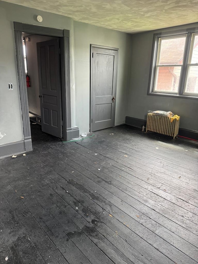 unfurnished room with radiator heating unit and hardwood / wood-style floors