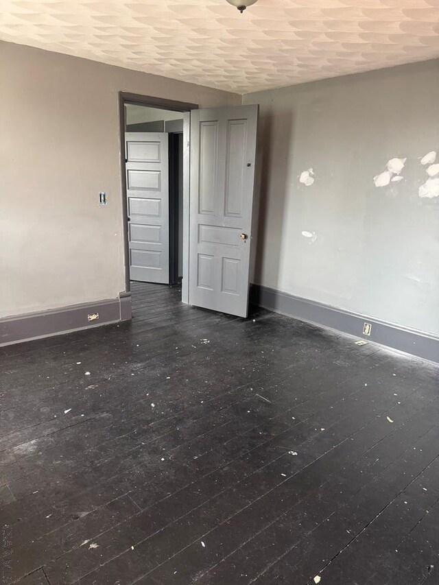unfurnished room featuring baseboards and dark wood-style floors