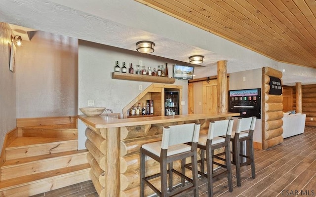 bar with wood finish floors, indoor wet bar, a textured ceiling, and wooden ceiling