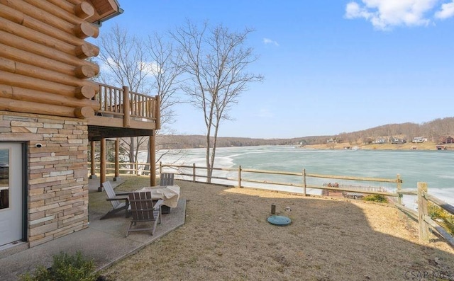 view of yard with fence, a balcony, and a water view