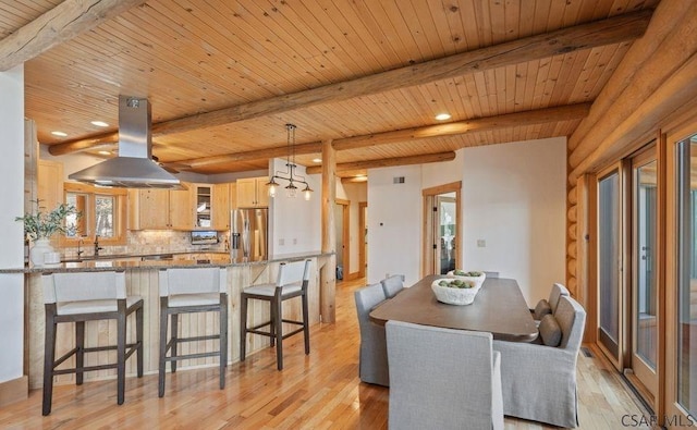 dining area with beam ceiling, light wood-style floors, and rustic walls