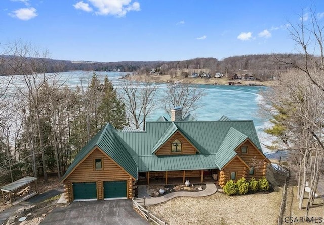 view of front of house featuring aphalt driveway, an attached garage, metal roof, log exterior, and a chimney