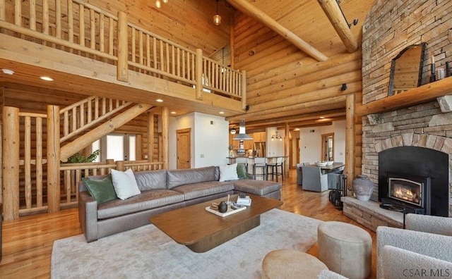 living area featuring a stone fireplace, wood ceiling, log walls, and light wood-style floors