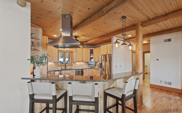 kitchen featuring backsplash, light brown cabinetry, a peninsula, island range hood, and stainless steel appliances