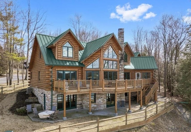 rear view of property with a standing seam roof, stone siding, log exterior, a patio area, and metal roof
