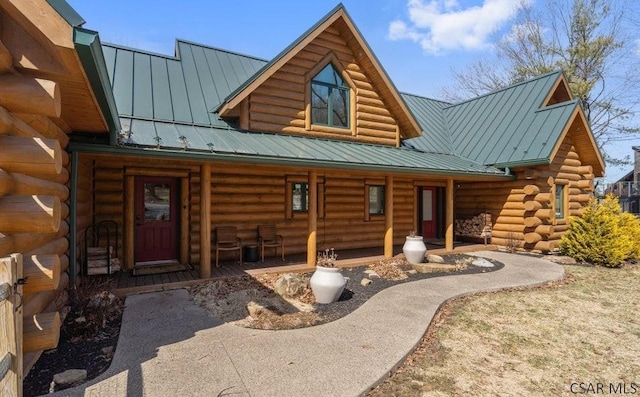 cabin featuring metal roof, a porch, log exterior, and a standing seam roof