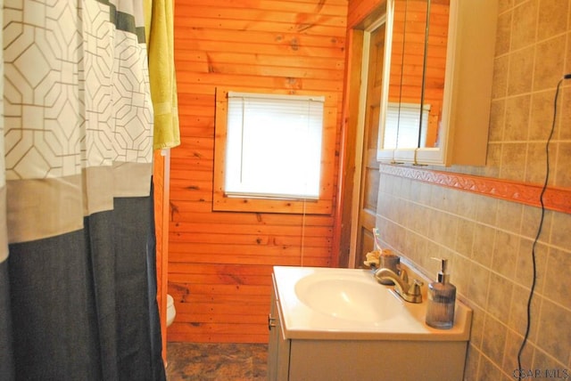 bathroom with vanity, toilet, and wood walls