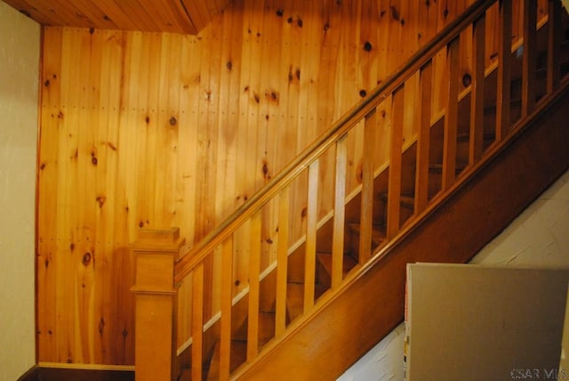 stairway featuring wood ceiling and wood walls