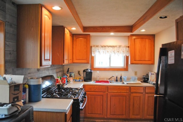 kitchen featuring a raised ceiling, sink, and black appliances