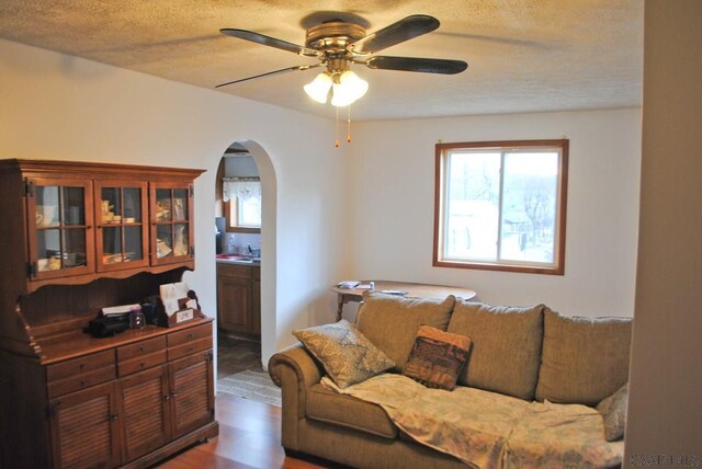 living room featuring dark hardwood / wood-style flooring, a textured ceiling, and ceiling fan