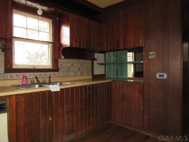 kitchen with dark wood-style flooring, a sink, light countertops, dishwasher, and tasteful backsplash