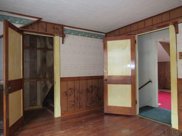 spare room featuring wainscoting, wood walls, and wood finished floors