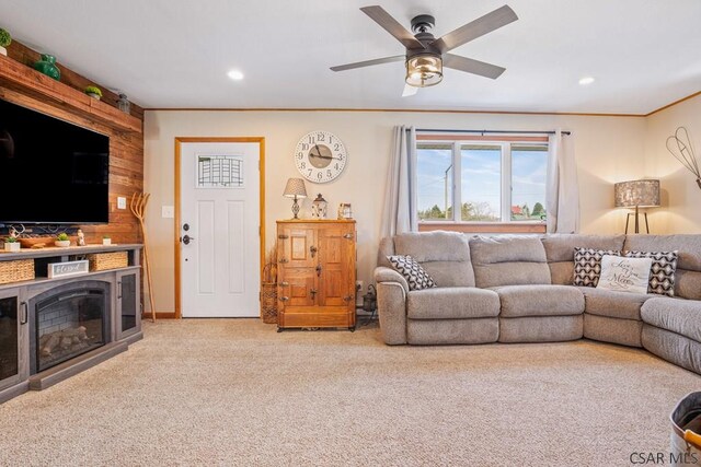 living area featuring ornamental molding, a glass covered fireplace, carpet flooring, and recessed lighting