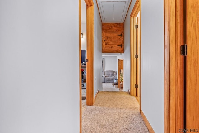 corridor with attic access, carpet floors, and baseboards