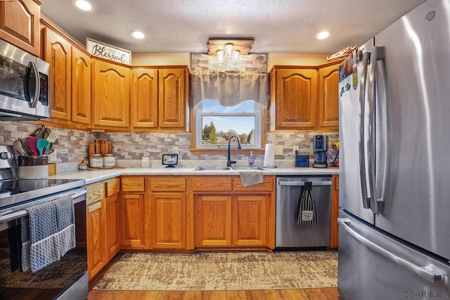 kitchen with brown cabinetry, appliances with stainless steel finishes, light countertops, and a sink