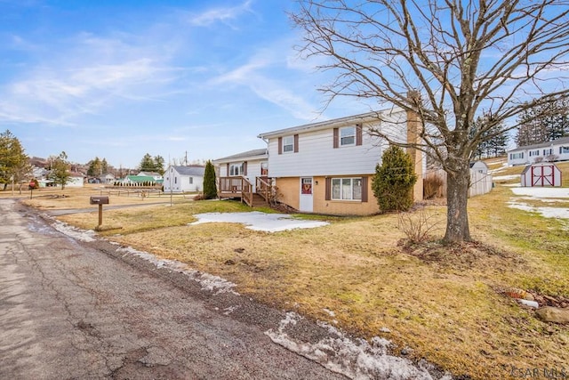 tri-level home featuring a front yard, fence, and brick siding