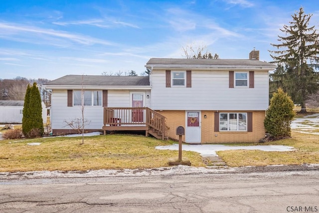 split level home with a chimney, a front lawn, and brick siding